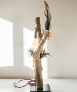 Lámpara artesanal de mesa hecha a mano con madera de deriva, cuidadosamente seleccionada, tratada y saneada. Sobre un soporte de hierro reciclado de astilleros navales y decoradas con preciosas plantas de aire.